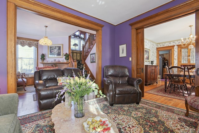 living area featuring a chandelier, wood finished floors, stairs, and crown molding