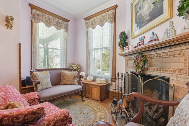 sitting room featuring light wood-style floors, a brick fireplace, and crown molding