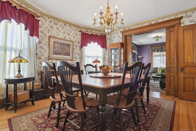 dining room with wallpapered walls, crown molding, wood finished floors, and an inviting chandelier