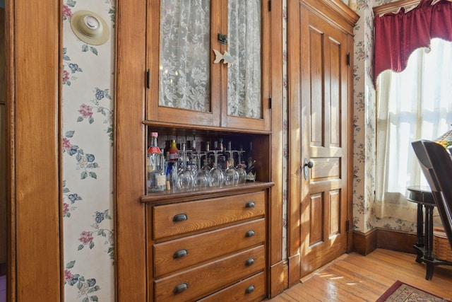 bar with light wood finished floors, wallpapered walls, baseboards, and a wealth of natural light