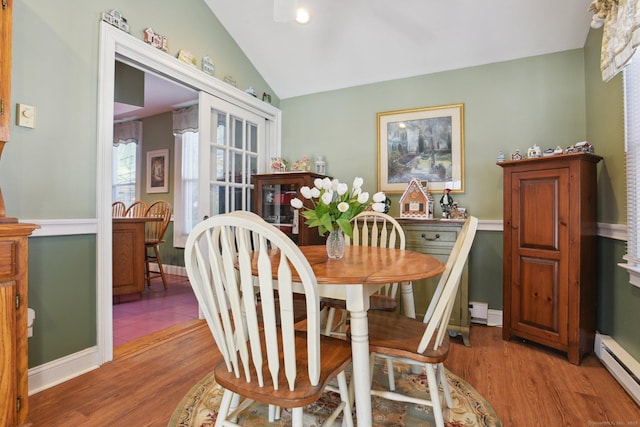 dining space with lofted ceiling, baseboards, baseboard heating, and wood finished floors