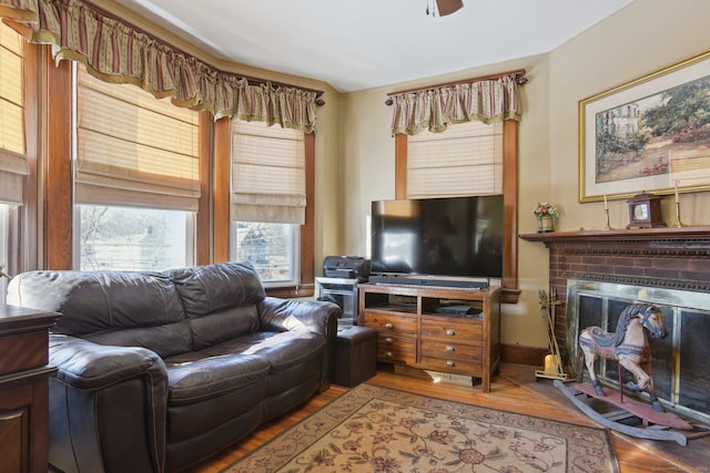 living room featuring a brick fireplace, baseboards, and wood finished floors