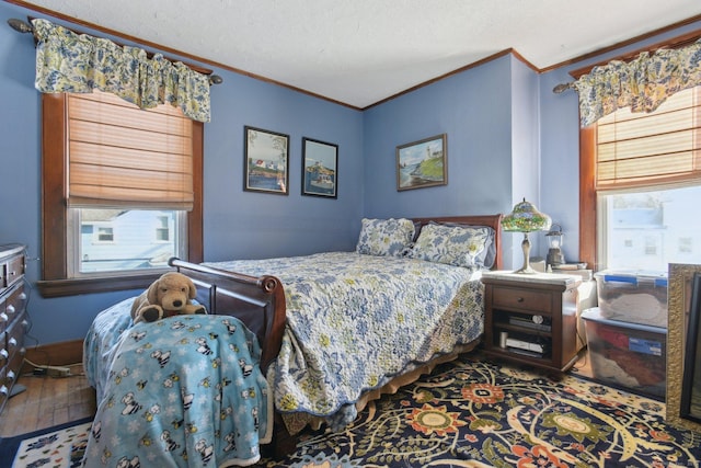 bedroom featuring ornamental molding, multiple windows, a textured ceiling, and wood finished floors