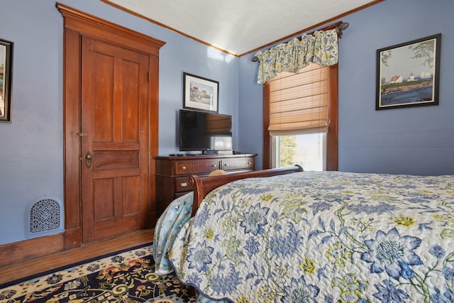 bedroom featuring ornamental molding, wood finished floors, and visible vents