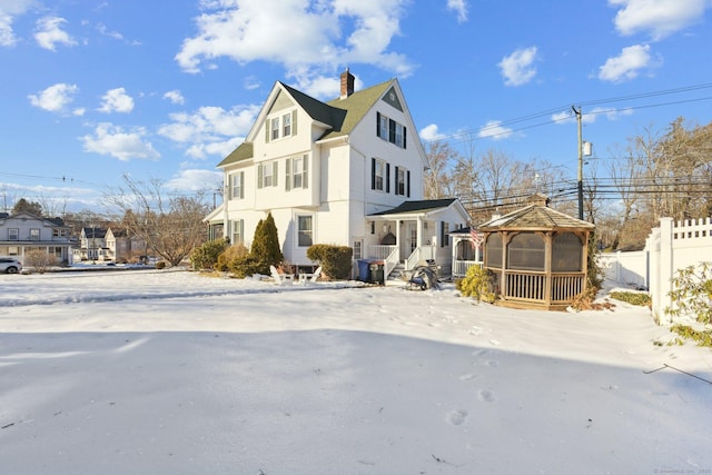 view of front of home featuring a gazebo, a chimney, fence, and a residential view