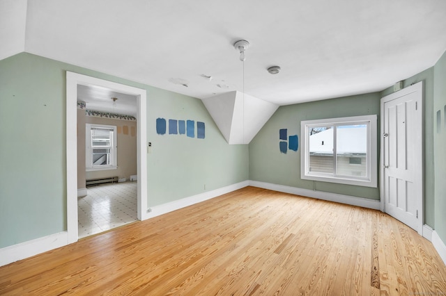 additional living space with wood-type flooring, vaulted ceiling, and baseboard heating