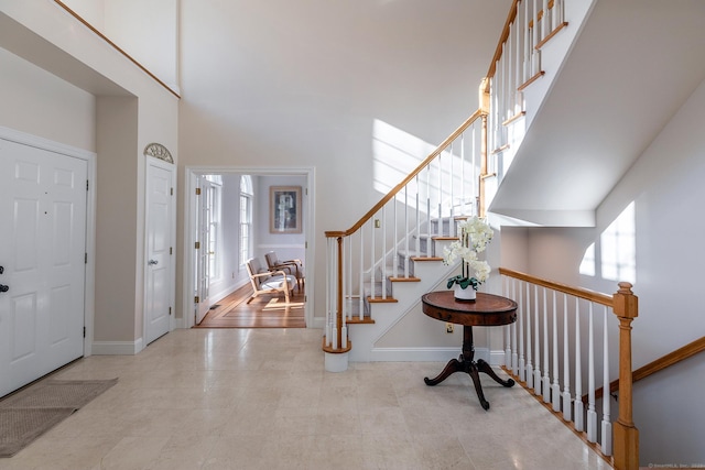 foyer featuring stairs, a high ceiling, and baseboards