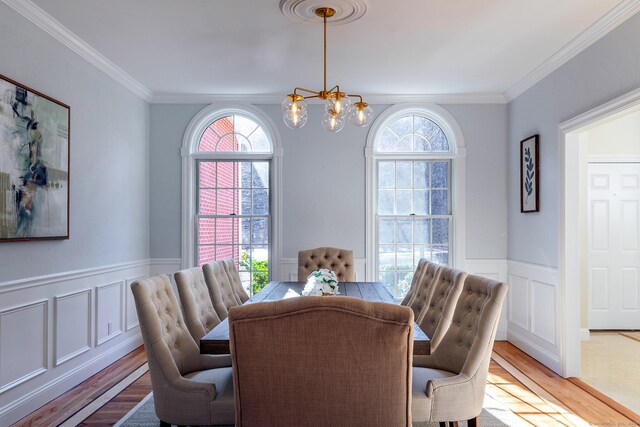 dining space featuring a wainscoted wall, wood finished floors, a wealth of natural light, and a notable chandelier