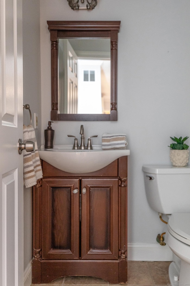 half bath with vanity, toilet, and baseboards