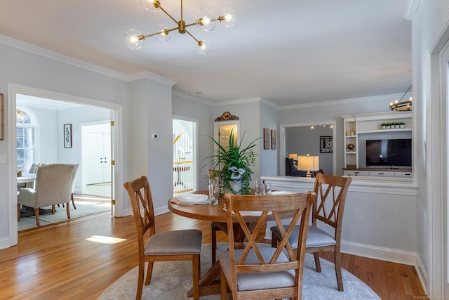 dining area featuring light wood finished floors, baseboards, a chandelier, and crown molding