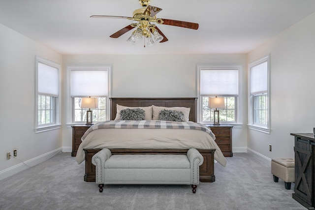 bedroom with light carpet, multiple windows, and baseboards