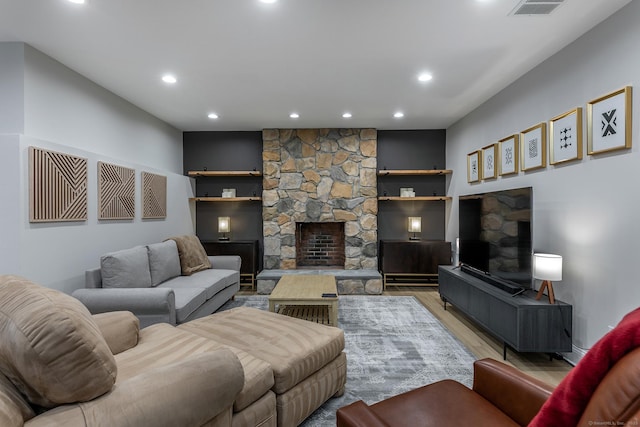 living area featuring recessed lighting, light wood-style flooring, visible vents, and a stone fireplace