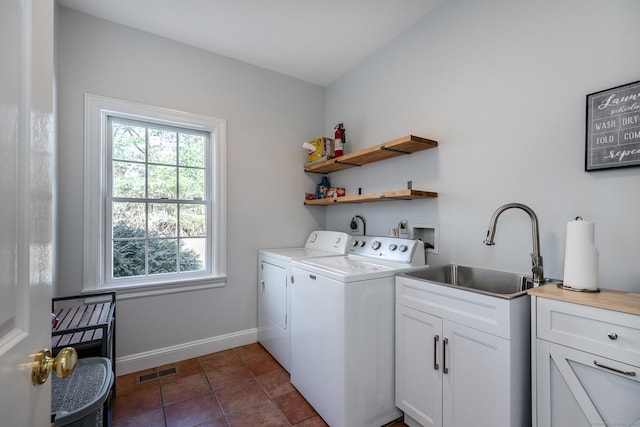 laundry area featuring cabinet space, baseboards, visible vents, washing machine and clothes dryer, and a sink