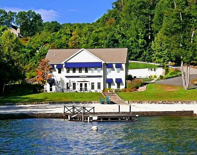 rear view of house with a water view and a lawn