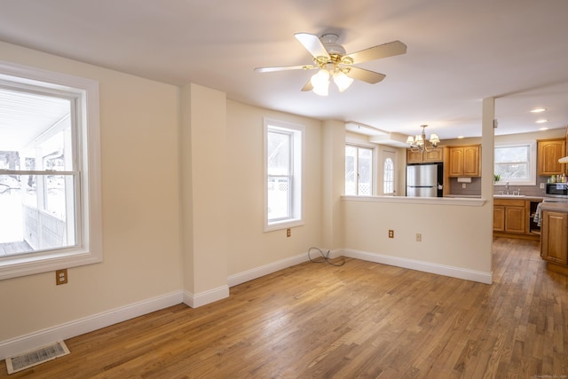 kitchen with baseboards, visible vents, light wood finished floors, stainless steel appliances, and brown cabinets