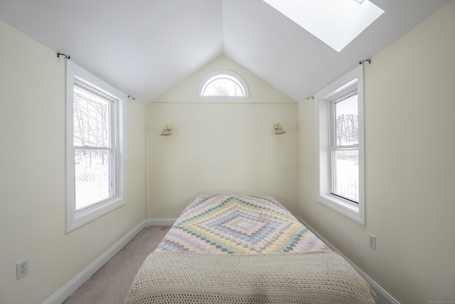 bedroom with lofted ceiling with skylight, multiple windows, light colored carpet, and baseboards