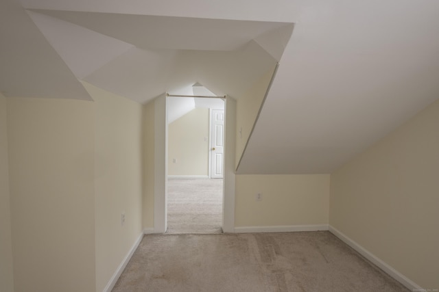 bonus room with lofted ceiling, light colored carpet, and baseboards