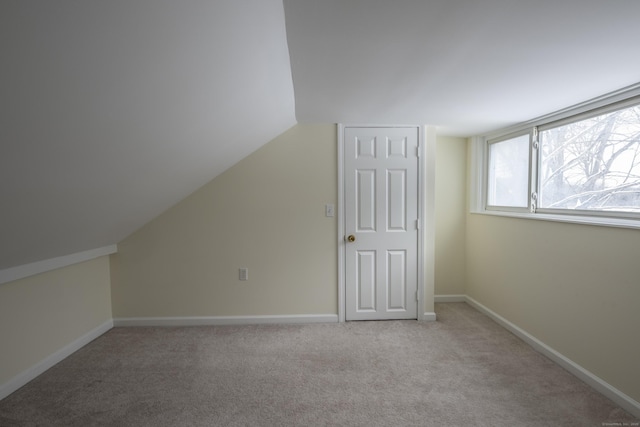 additional living space with light colored carpet, baseboards, and vaulted ceiling