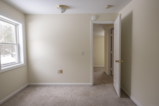 spare room with light colored carpet and baseboards