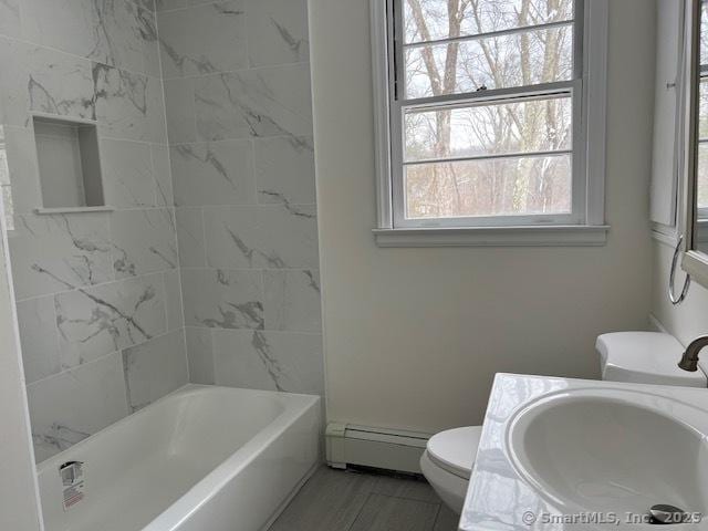 full bathroom featuring baseboard heating, tiled shower / bath, vanity, and toilet