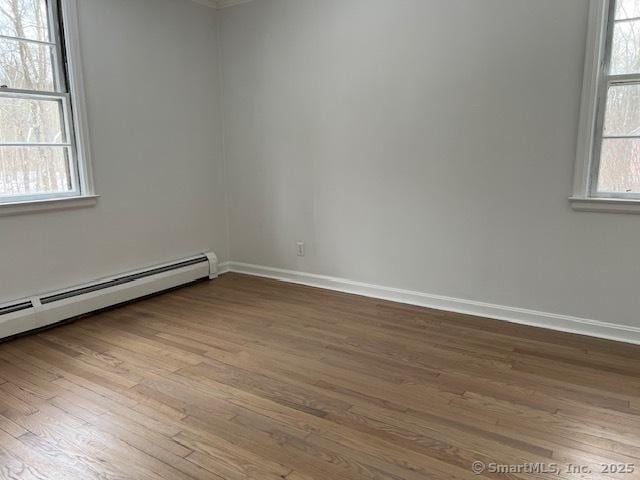 empty room featuring hardwood / wood-style floors and a baseboard heating unit