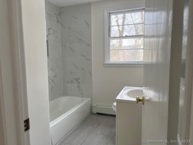 full bathroom with vanity, a baseboard heating unit, tiled shower / bath, and toilet