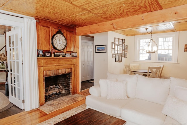 living room featuring an inviting chandelier, a brick fireplace, wood ceiling, and wood-type flooring