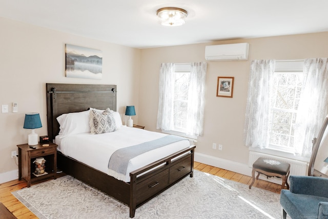 bedroom featuring a wall mounted AC and light hardwood / wood-style floors