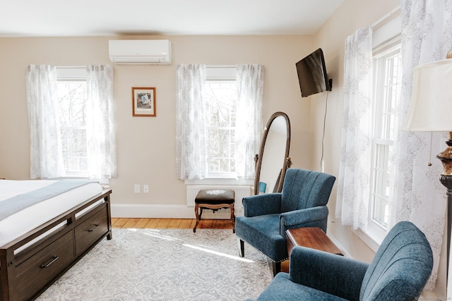 bedroom with a wall unit AC and light hardwood / wood-style floors