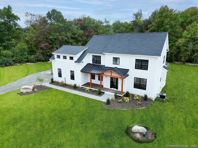 modern farmhouse with central AC unit, a front lawn, and covered porch