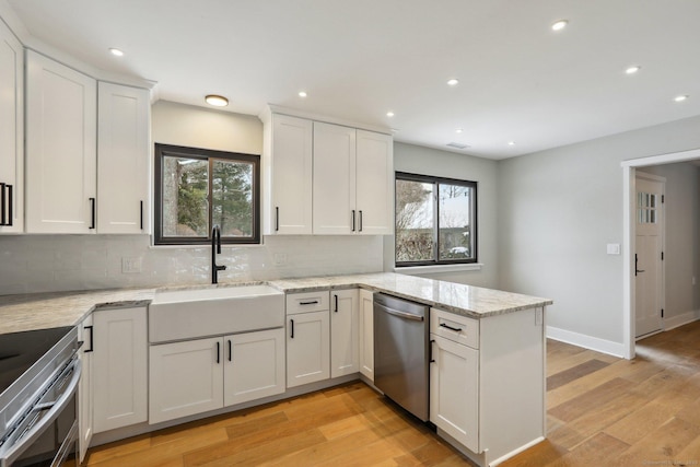 kitchen featuring sink, white cabinetry, appliances with stainless steel finishes, light stone countertops, and decorative backsplash