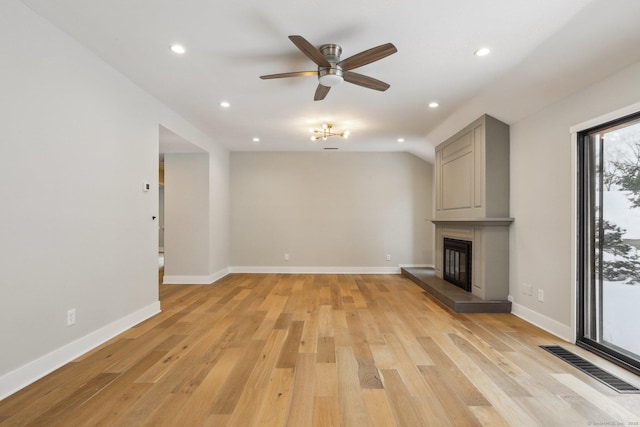 unfurnished living room with light hardwood / wood-style flooring, a large fireplace, and ceiling fan