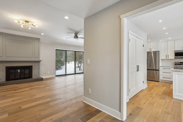 kitchen with light stone countertops, light hardwood / wood-style floors, white cabinets, and appliances with stainless steel finishes