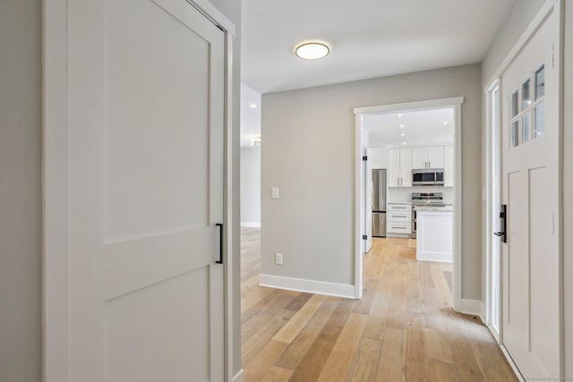 hall with baseboards and light wood-type flooring