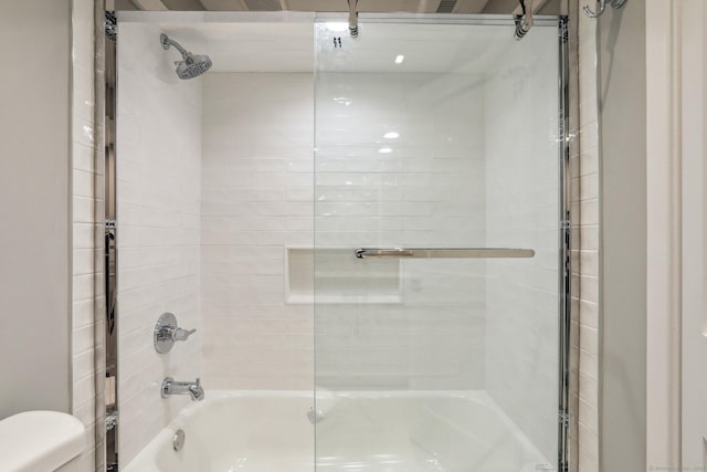 bathroom with combined bath / shower with glass door and toilet