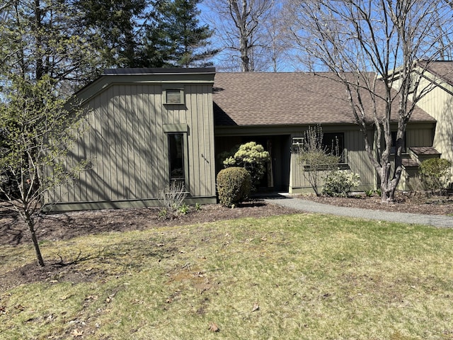 mid-century home with a shingled roof and a front yard