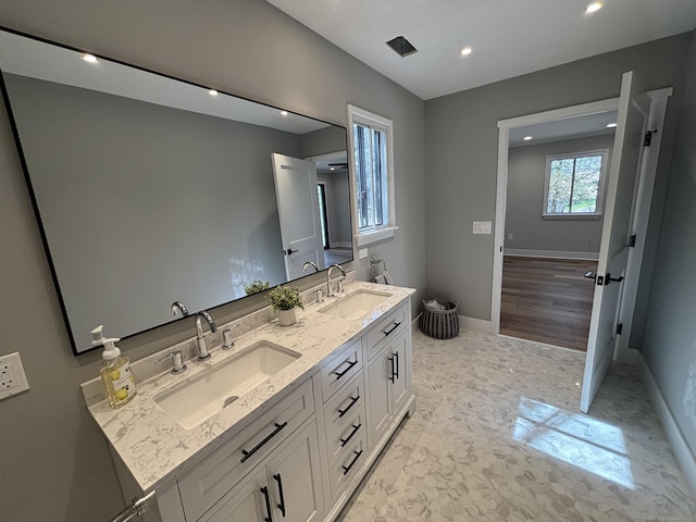 bathroom with baseboards, a sink, recessed lighting, and double vanity