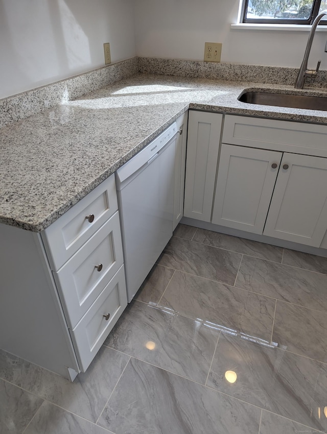 kitchen with dishwasher, marble finish floor, light stone counters, and a sink