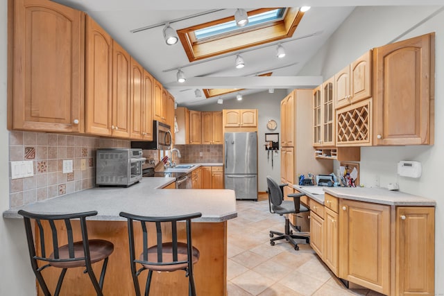 kitchen with built in desk, sink, a kitchen breakfast bar, kitchen peninsula, and stainless steel appliances