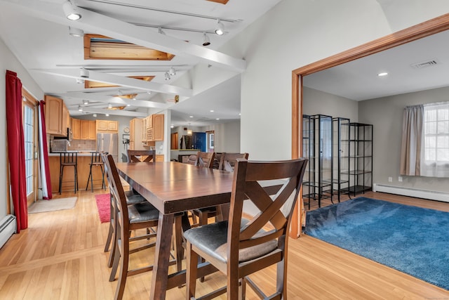 dining area with light hardwood / wood-style flooring, rail lighting, and a baseboard radiator