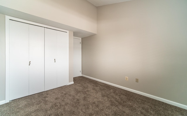 unfurnished bedroom with dark carpet and a closet