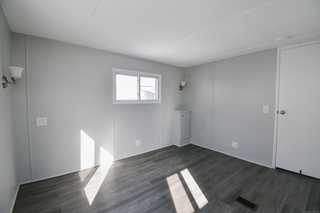 unfurnished room with dark wood-type flooring