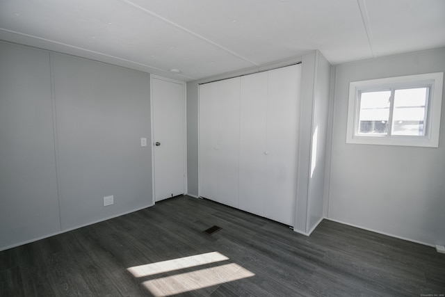 unfurnished bedroom with dark wood-type flooring and a closet