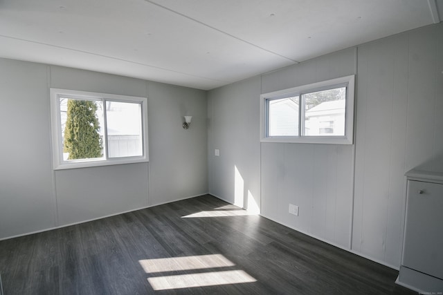 empty room featuring plenty of natural light and dark hardwood / wood-style flooring