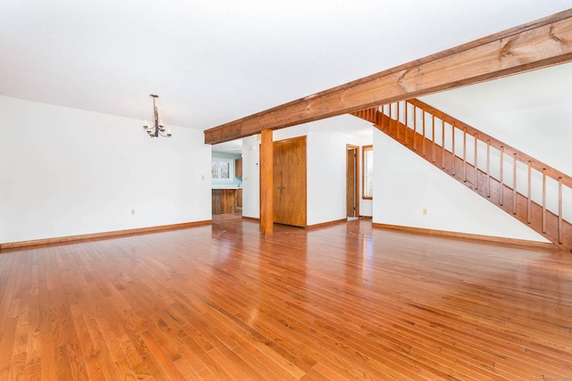 unfurnished living room featuring an inviting chandelier, wood-type flooring, and beamed ceiling