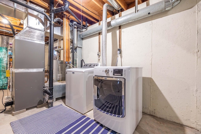 washroom featuring heating unit and washer and clothes dryer