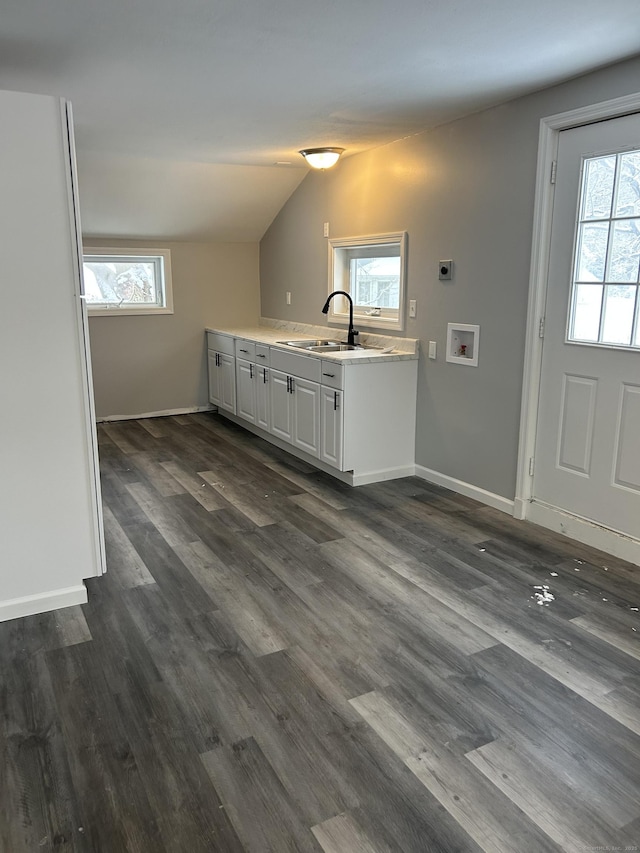 kitchen with light countertops, dark wood-type flooring, a sink, and white cabinetry