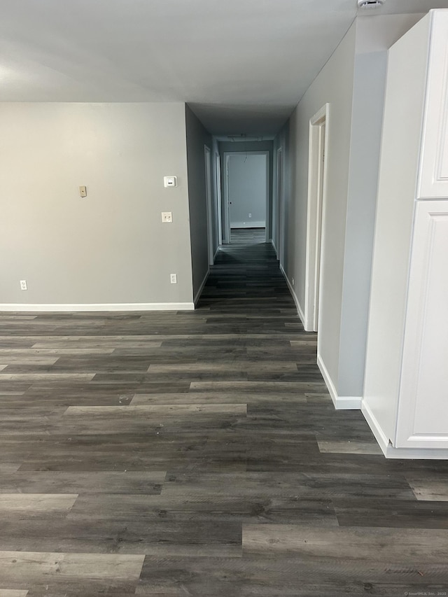 corridor featuring dark wood-style flooring and baseboards