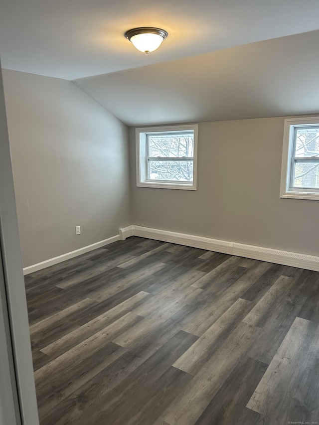 empty room with lofted ceiling, dark wood-style flooring, and baseboards