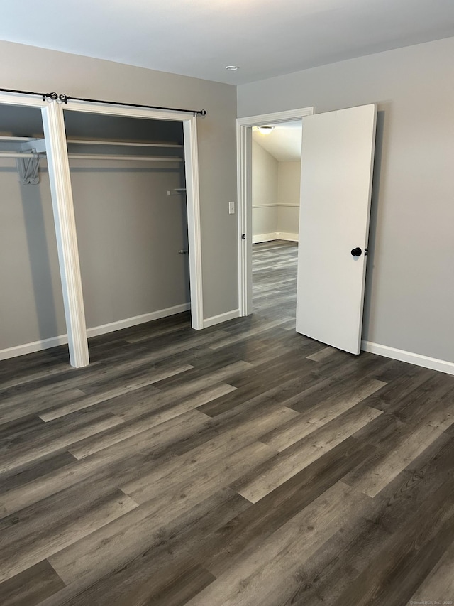 unfurnished bedroom with dark wood-style floors, baseboards, and multiple closets